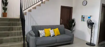 a living room with a gray chair with yellow pillows at AMI Homestay & Guest House in Gua Musang