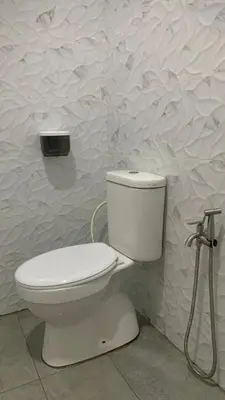 a white toilet in a bathroom with a wall at Bilik Umar in Gerik