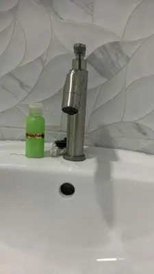 a faucet and a green bottle on a sink at Bilik Ubaidillah in Gerik