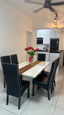 a dining room table with chairs and a vase with red flowers at Meritus - Perai in Perai