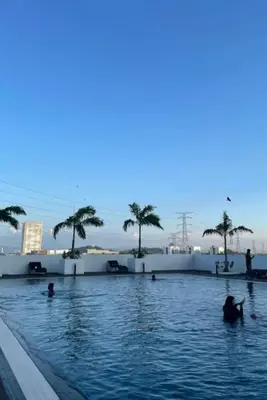a pool with palm trees and people in the water at Meritus - Perai in Perai