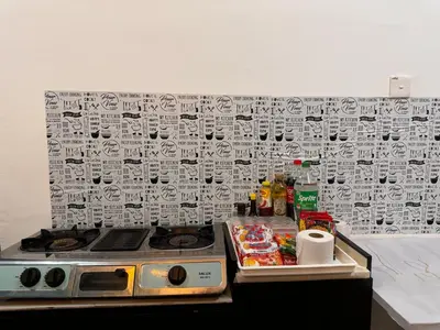 a kitchen counter with a stove and a wall with graffiti at skyview relax 2BR 1car park arenaspice airport domestic guest only in Bayan Lepas