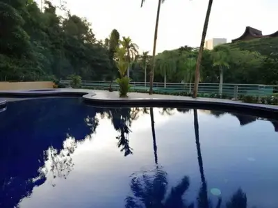 a pool with a reflection of trees in the water at Sri Sayang at Batu Feringghi Beach by Plush in Ayer Itam