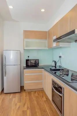 a kitchen with a white refrigerator and wooden cabinets at Sri Sayang at Batu Feringghi Beach by Plush in Ayer Itam