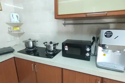 a kitchen with a stove with two pots and a microwave at 66 Homestay 5 Min to Leaning Tower in Teluk Intan