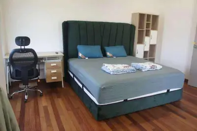 a bedroom with a bed with a green headboard and a desk at Tranquil lake view retreat \u601d\u6e56\u8336\u5c4b in Ipoh