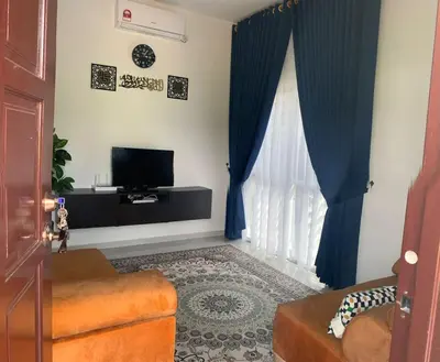 a living room with a television and blue curtains at HomeStay Damia in Teluk Intan