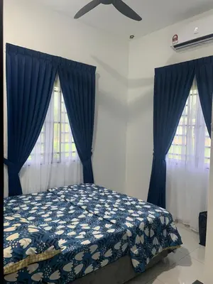 a bedroom with a bed with blue curtains and a ceiling fan at HomeStay Damia in Teluk Intan