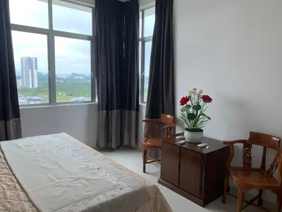 a bedroom with a bed and a table with flowers on it at The Rain Homestay Meru Raya in Ipoh