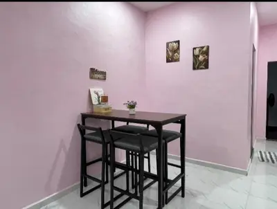 a table in a room with a pink wall at Ammaiti Homestay Kulim in Kulim