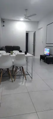 a room with a table and chairs and a screen at Meritus Seaview Apartment in Perai
