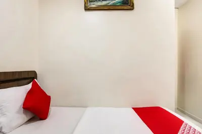 a bed with a red pillow and a picture on the wall at Super OYO 89427 Kavanas Hotel Taiping in Taiping