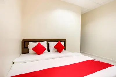 a bed with red pillows in a white room at Super OYO 89427 Kavanas Hotel Taiping in Taiping