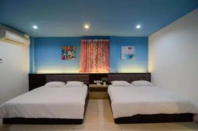 two beds in a room with blue walls and a window at Ting Residence in Sitiawan