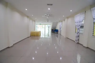 a hallway with white tile floors and a yellow chair at Ting Residence in Sitiawan