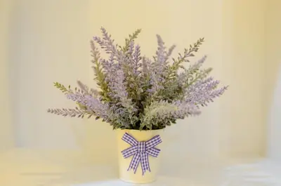 a white vase with purple flowers in it at Ting Residence in Sitiawan