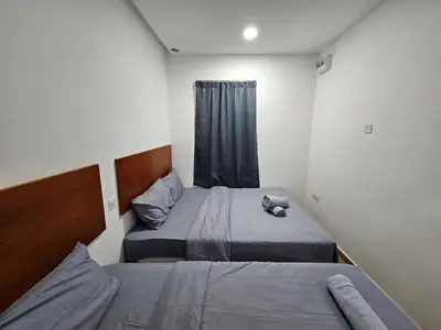 two beds in a small room with a window at New Mawlaya Hotel Penang in Gelugor