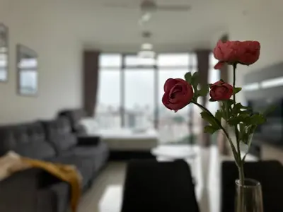 a vase with three roses in a living room at Beacon Executive Suites by WL in Kampong Makam