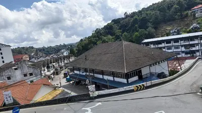 a building on the side of a street next to a mountain at Ria Cameron Hotel in Cameron Highlands