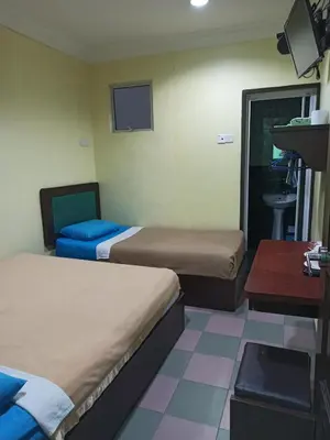 a room with two beds and a table and a sink at Ria Cameron Hotel in Cameron Highlands