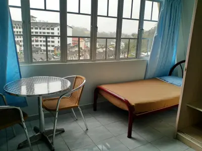 a room with a bed and a table and a window at Ria Cameron Hotel in Cameron Highlands