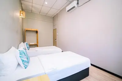 two beds in a room with white walls at Swing & Pillows - 87 Chulia St, Georgetown Penang in George Town