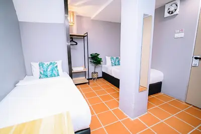 a room with two beds and an orange floor at Swing & Pillows - 87 Chulia St, Georgetown Penang in George Town