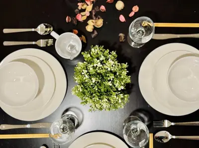 a table with white plates and glasses and a plant at Georgetown Seaview 5 Min To Gurney N Straits Quay Washing Machine N Dryer in Tanjong Tokong