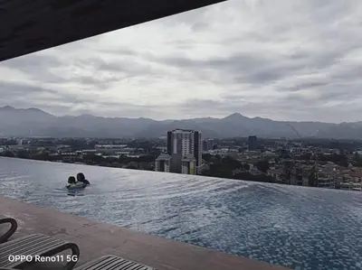 two people sitting on the edge of a swimming pool on a building at Veneto Ipoh homestay 3BR with infinity pool in Ipoh