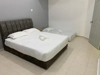 two beds in a bedroom with white sheets and pillows at Eco Homestay in Teluk Intan