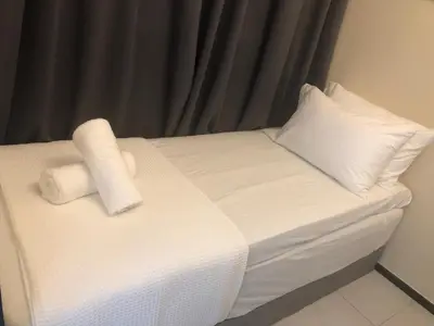 a bed with two rolls of white sheets and pillows at Urban Suite Condominium By Blue Sky Holidays in Jelutong