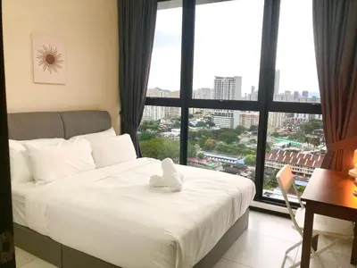 a bed with a teddy bear on it in front of a window at Urban Suite Condominium By Blue Sky Holidays in Jelutong
