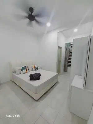 a white bedroom with a bed and a ceiling fan at Yarra SP Homestay in Sungai Petani
