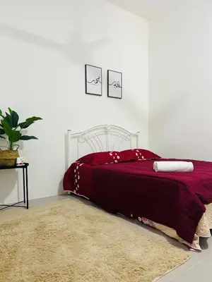 a bedroom with a bed with a red blanket and a rug at Casa Kita Homestay in Bandar Baharu
