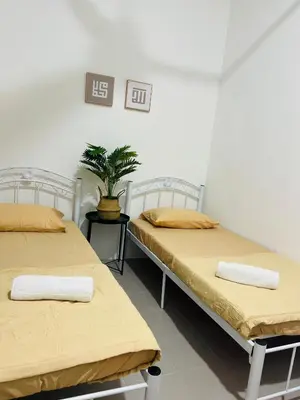 two beds in a room with a potted plant at Casa Kita Homestay in Bandar Baharu