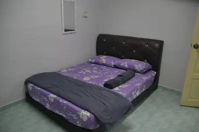 a bed in a room with a purple comforter at Yim's Homestay in Kuala Kubu Baharu