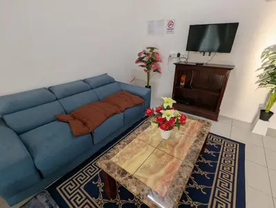 a living room with a blue couch and a table at HOMESTAY IBUNDA Sabak Bernam in Sabak Bernam