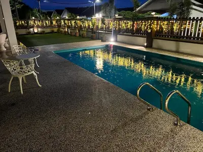 a swimming pool at night with a table and a chair at Legreene Ipoh 15pax in Tambun