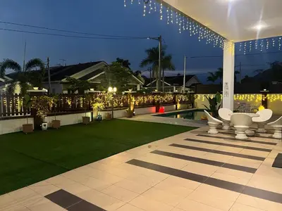 a patio with a lawn and a pool at night at Legreene Ipoh 15pax in Tambun
