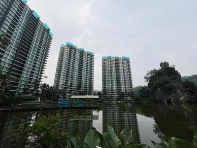 two tall apartment buildings next to a body of water at Ipoh Lakeside Apartment with Mountain View in Kampong Batu Lapan