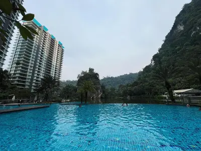 a large blue swimming pool with mountains in the background at Ipoh Lakeside Apartment with Mountain View in Kampong Batu Lapan