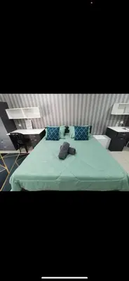 a bed with a green blanket and blue pillows at Zaf's Stay in Kampong Malim Nawar