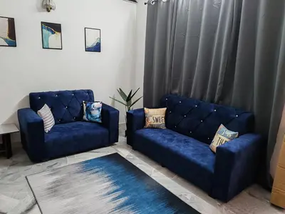 a living room with two blue couches and a rug at Busybee Breezy Stay Homestay in Ipoh