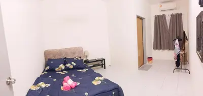 a bedroom with a bed with a blue comforter and flowers at Ceq Atiah Homestay in Seri Iskandar