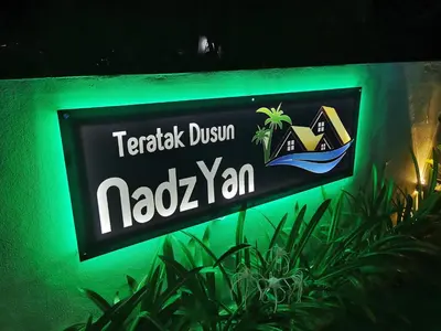 a sign for a noda yan on a green wall at Teratak Dusun NadzYan in Bukit Selambau