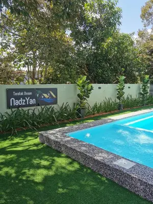 a swimming pool in a yard next to a fence at Teratak Dusun NadzYan in Bukit Selambau