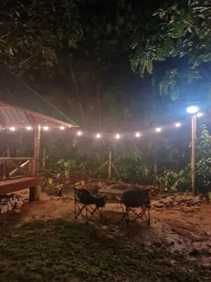 a table and two chairs in a yard at night at Zue Rra Hidden Retreat in Kampong Kuala Chegar
