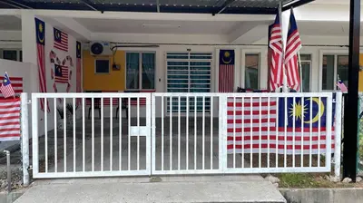 a white gate in front of a house with flags at Amad Homestay in Kuala Lipis