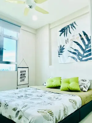 a bedroom with a bed with green pillows on it at Arena guesthouse in Bayan Lepas