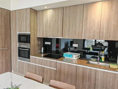 a kitchen with wooden cabinets and a counter top at By The Sea Beach Front Sea view Apartment 3 in Batu Ferringhi